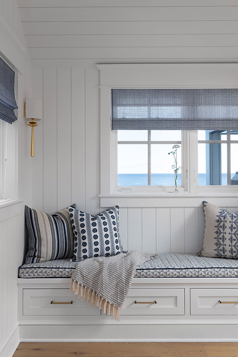 Built-in window seat with blue and white patterned cushions and pillows, overlooking the lake