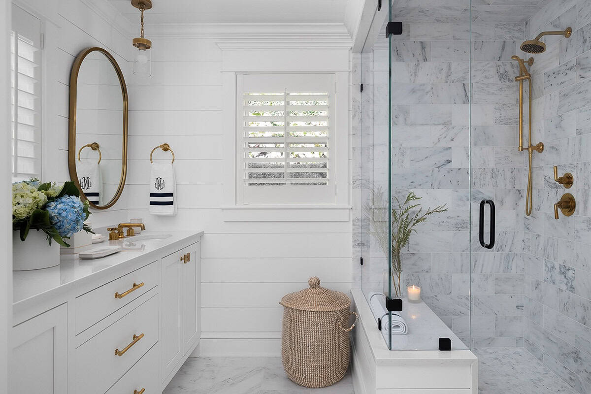White bathroom with shiplap walls, gold fixtures, oval mirror, and marble-tiled walk-in shower