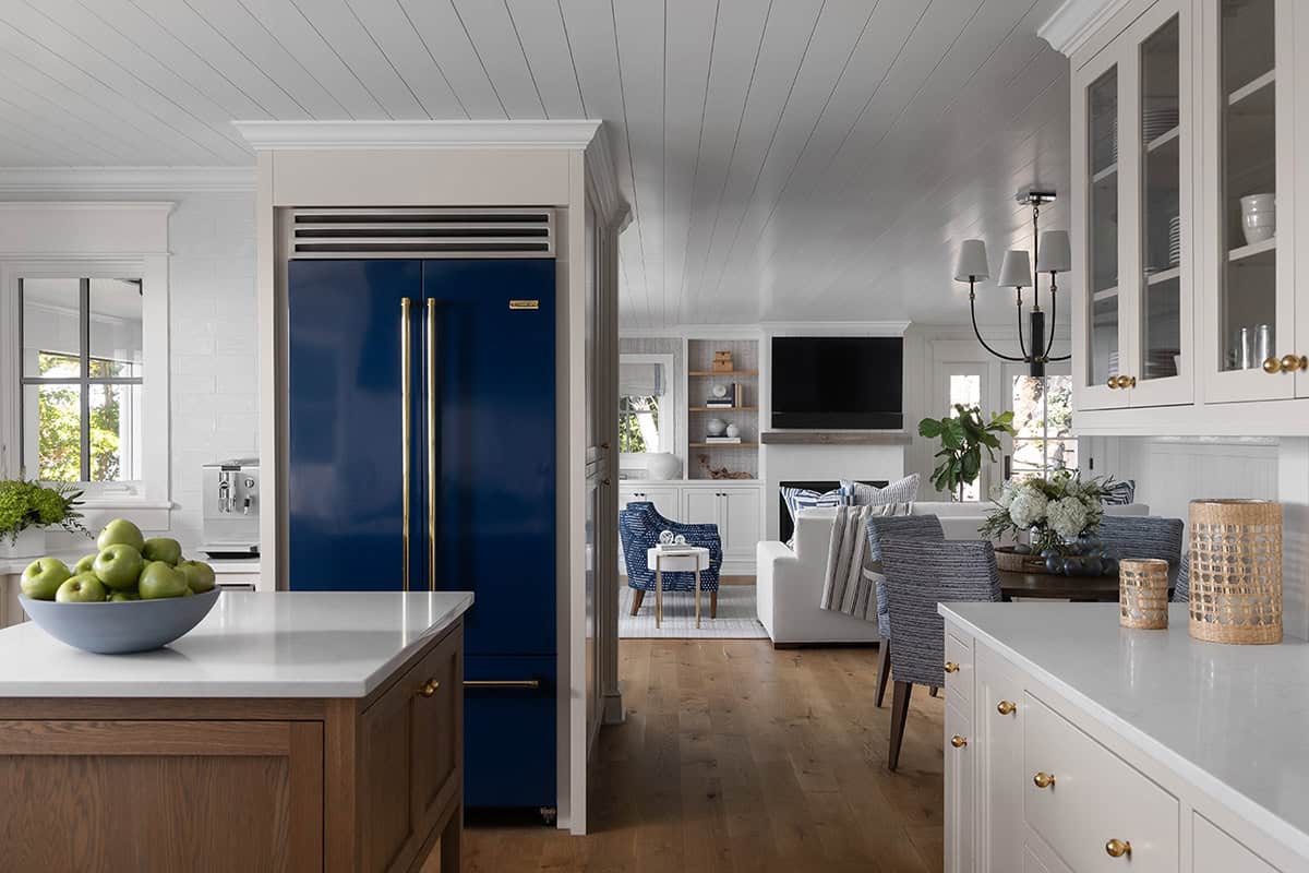 Kitchen and living area with a navy blue built-in refrigerator, white cabinetry, and wood flooring