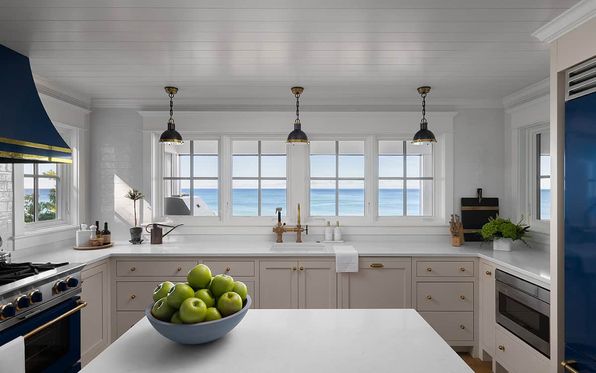 Kitchen counter with a bowl of green apples and a wall of windows framing a Lake Michigan view