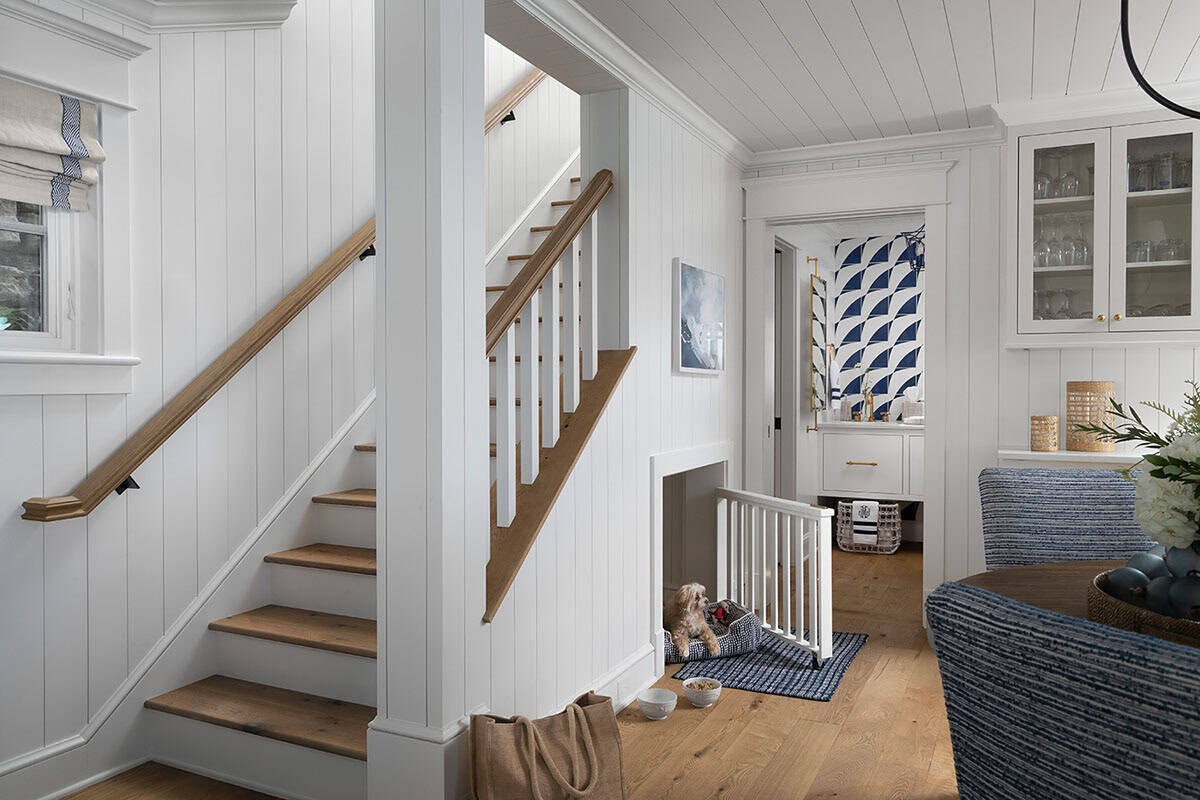 Entryway with wood staircase, shiplap walls, built-in dog nook with small dog, and patterned blue wallpaper beyond