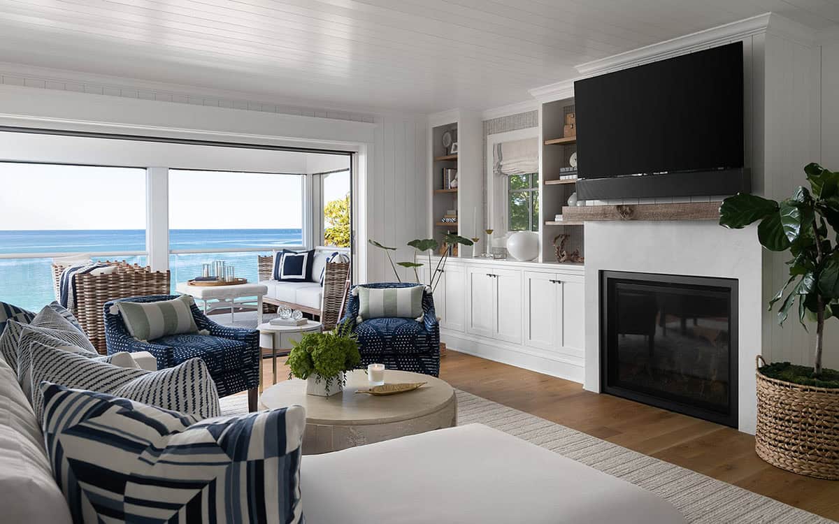 Living room with built-in white shelving, fireplace with TV above, and open sliding doors to a lake-view deck