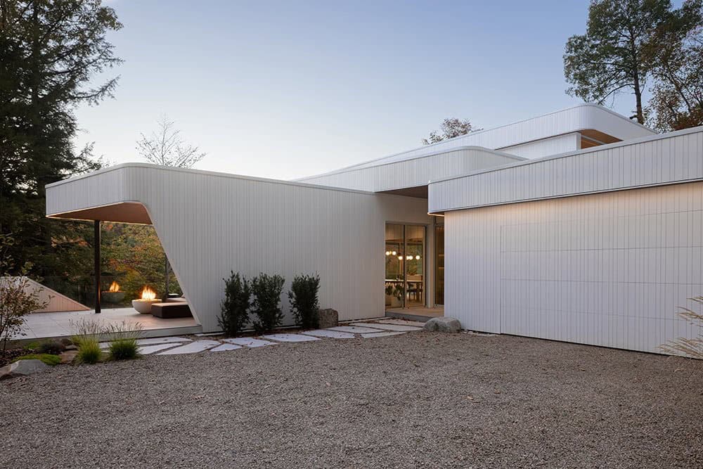 Front entrance of contemporary white home at dusk with stepping stone path and covered patio