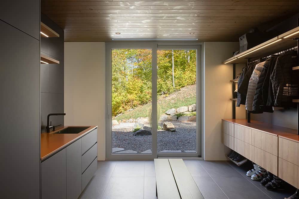 Well-organized mudroom with copper countertop, dark cabinetry, coat storage, and sliding glass door to garden
