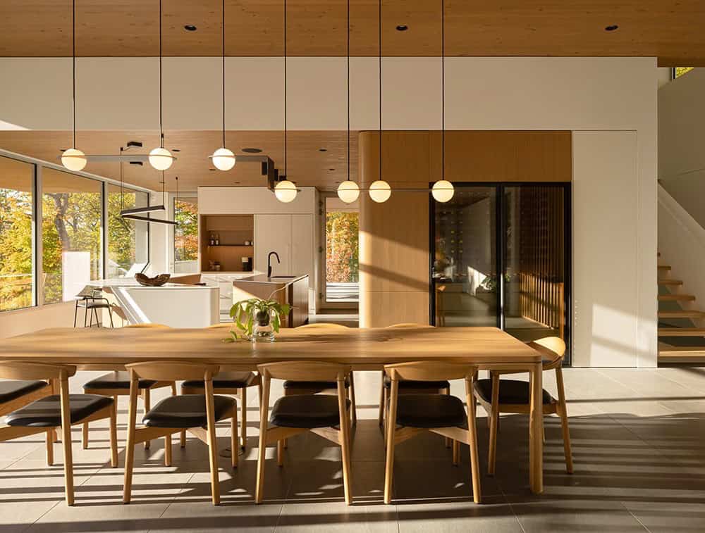 Dining area with large live-edge wood table, globe pendant lights, and open-plan kitchen beyond