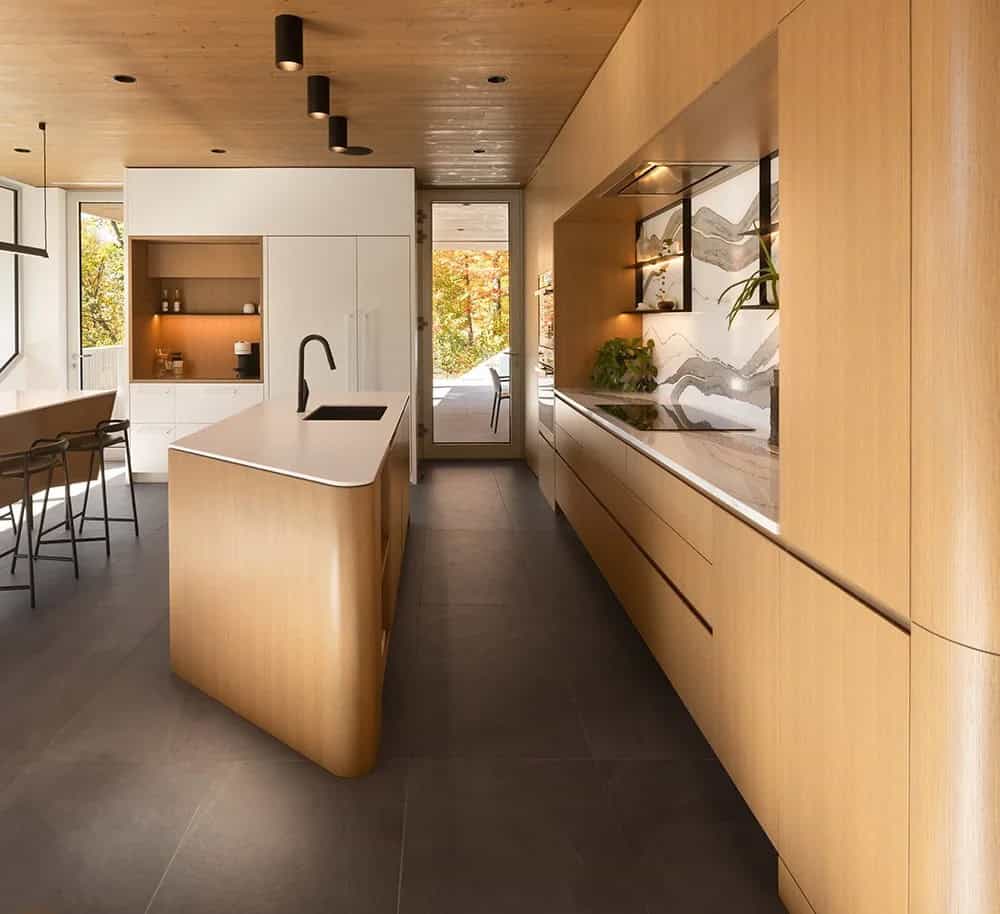 Modern kitchen with curved light wood island, marble-look backsplash, and black matte faucet
