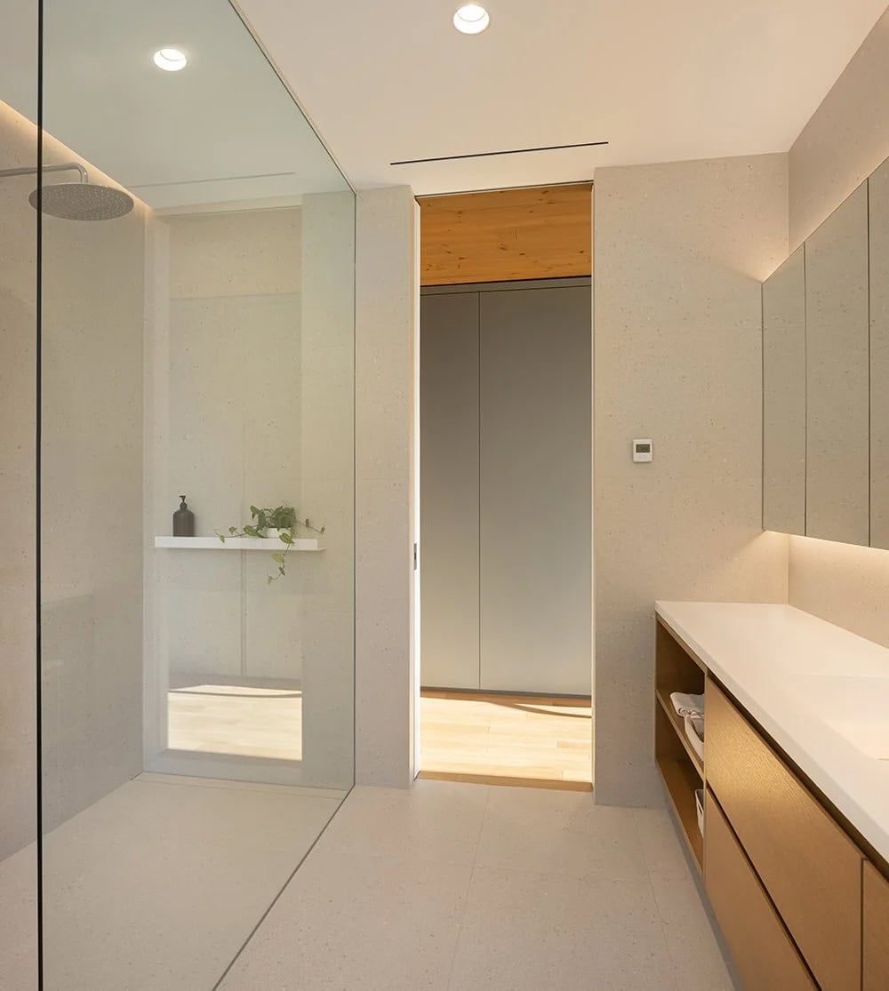 Serene ensuite bathroom with walk-in rain shower, stone tile walls, and passage to walk-in closet