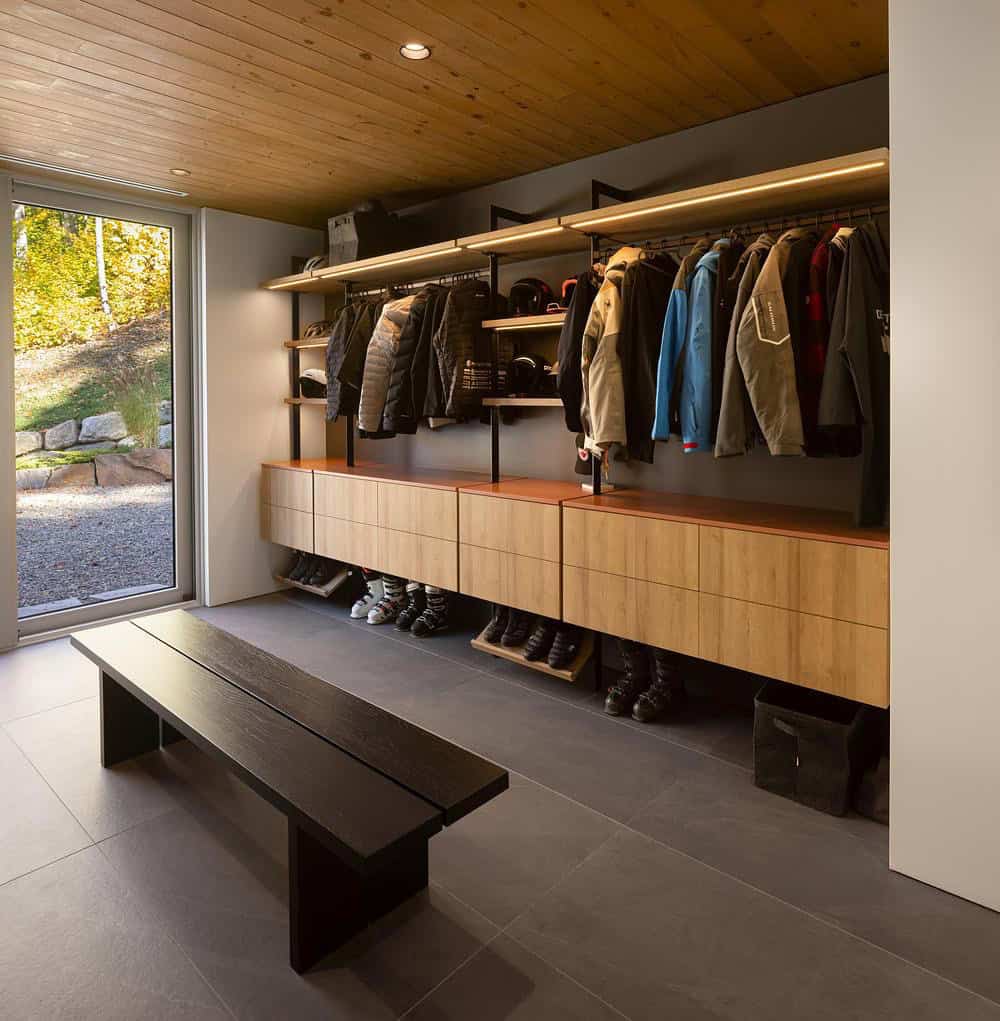 Spacious ski gear mudroom with open coat rails, copper-topped wood drawers, shoe storage, and dark bench