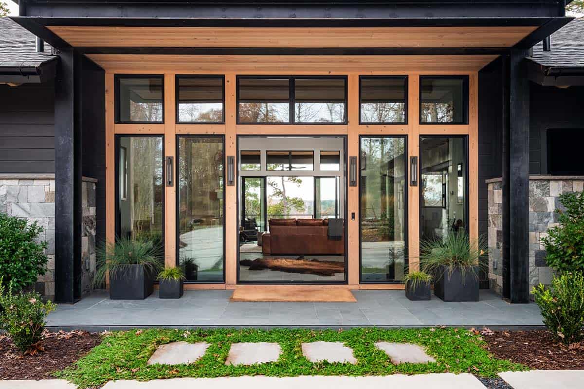 Modern lakehouse entry with floor-to-ceiling glass doors and cedar wood overhang