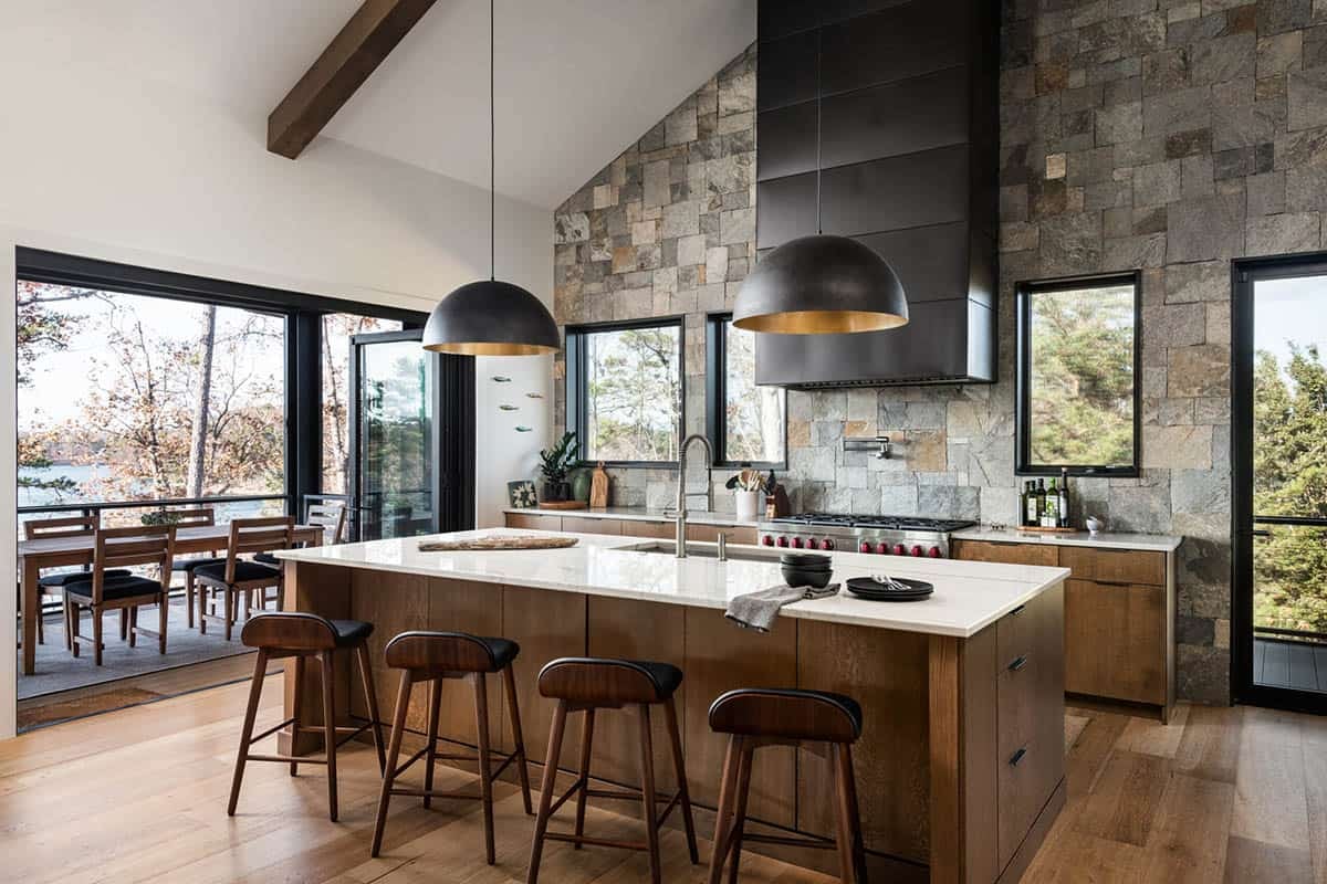 Kitchen island with wood barstools beneath black dome pendant lights
