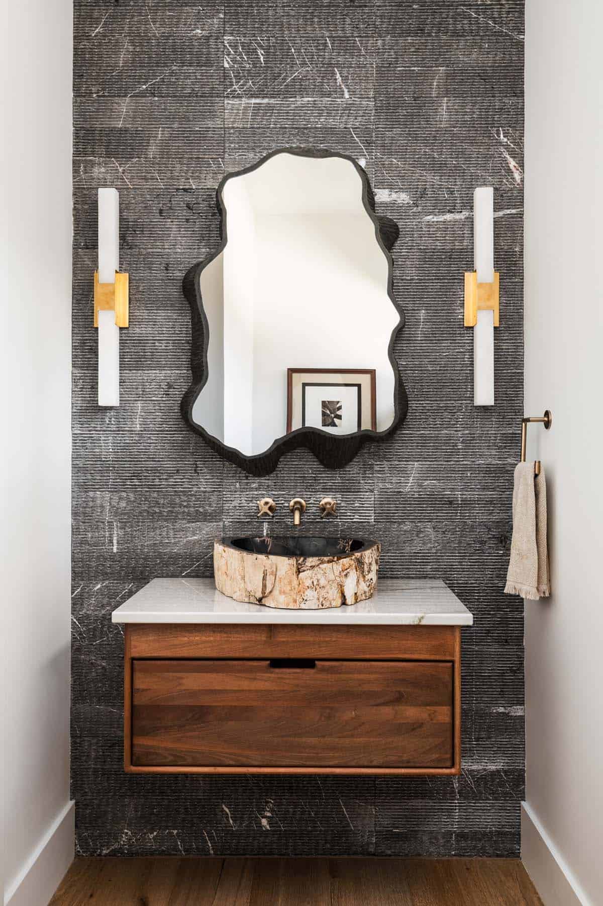 Powder room with petrified wood vessel sink and dark textured stone wall