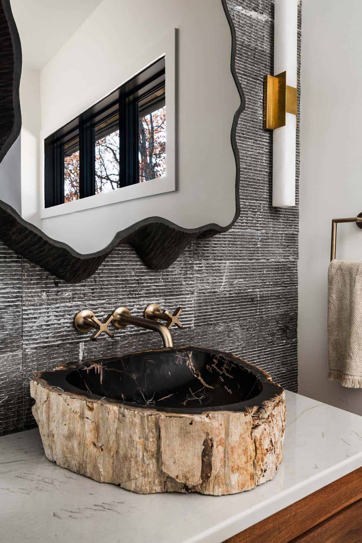 Close-up of petrified wood sink with brass faucet and stone wall