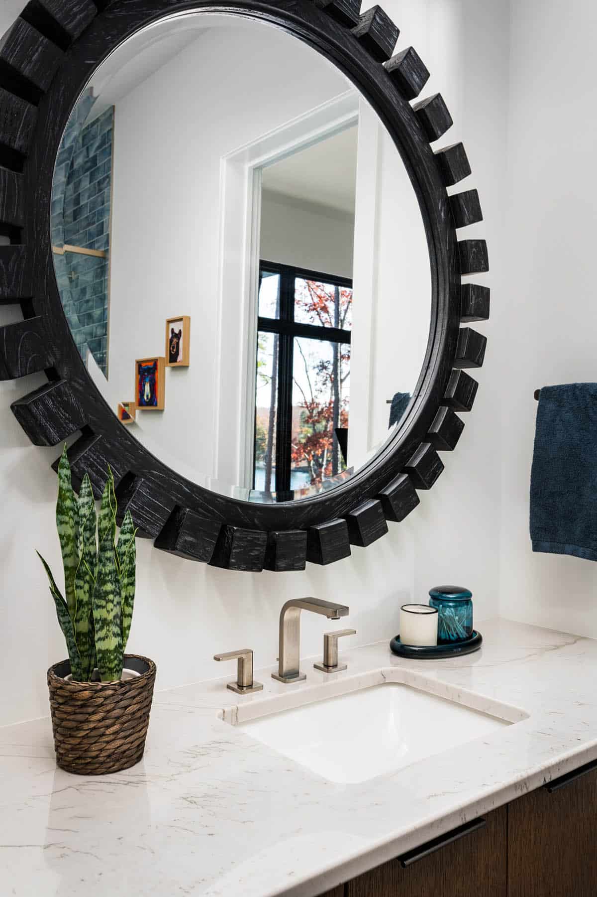 Round wooden mirror above bathroom sink with potted plant