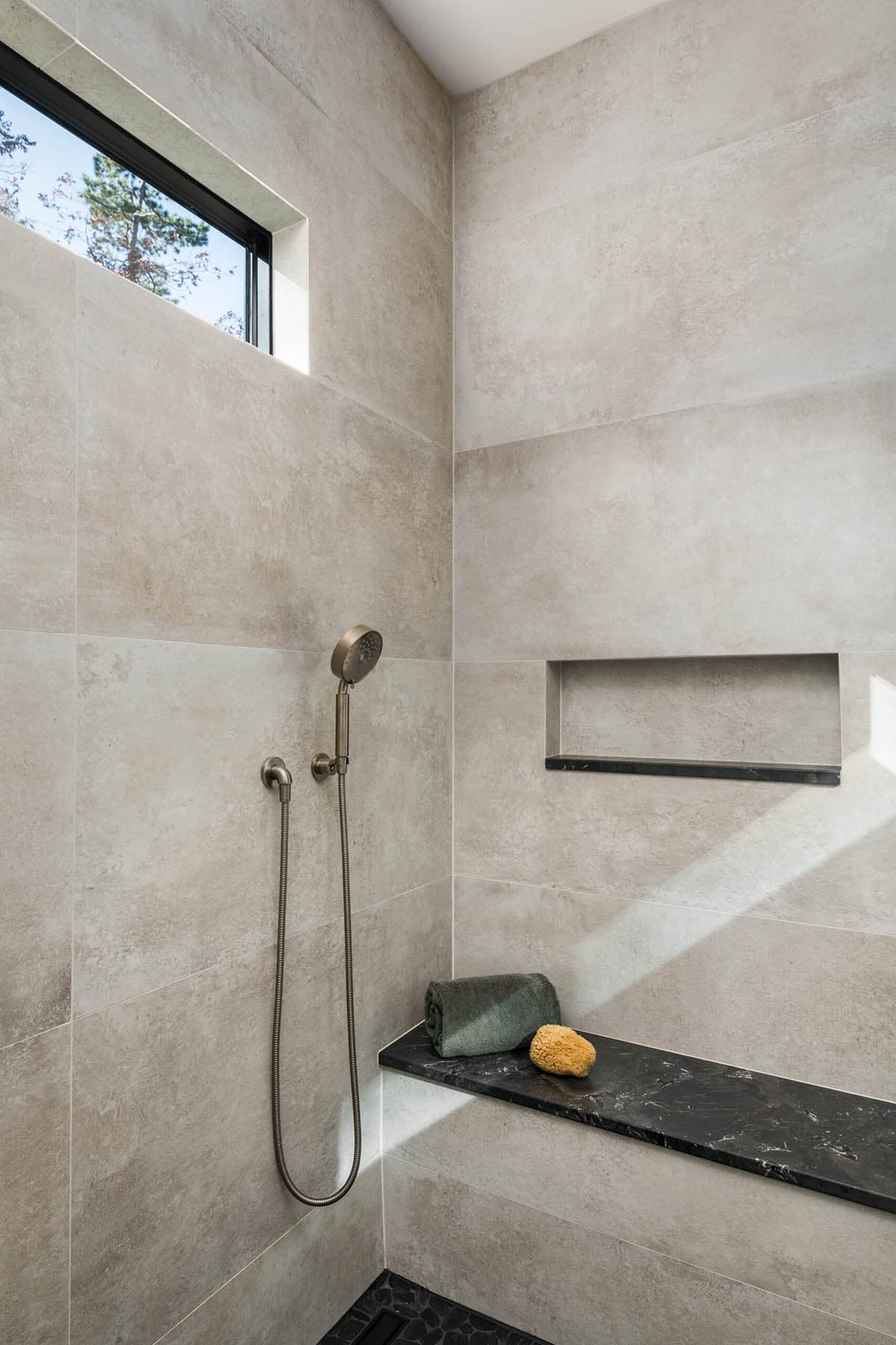 Shower niche detail with black stone bench and natural tile