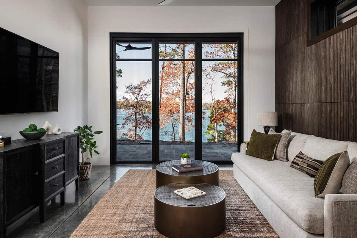 Living area with sliding glass doors framing lake and autumn trees