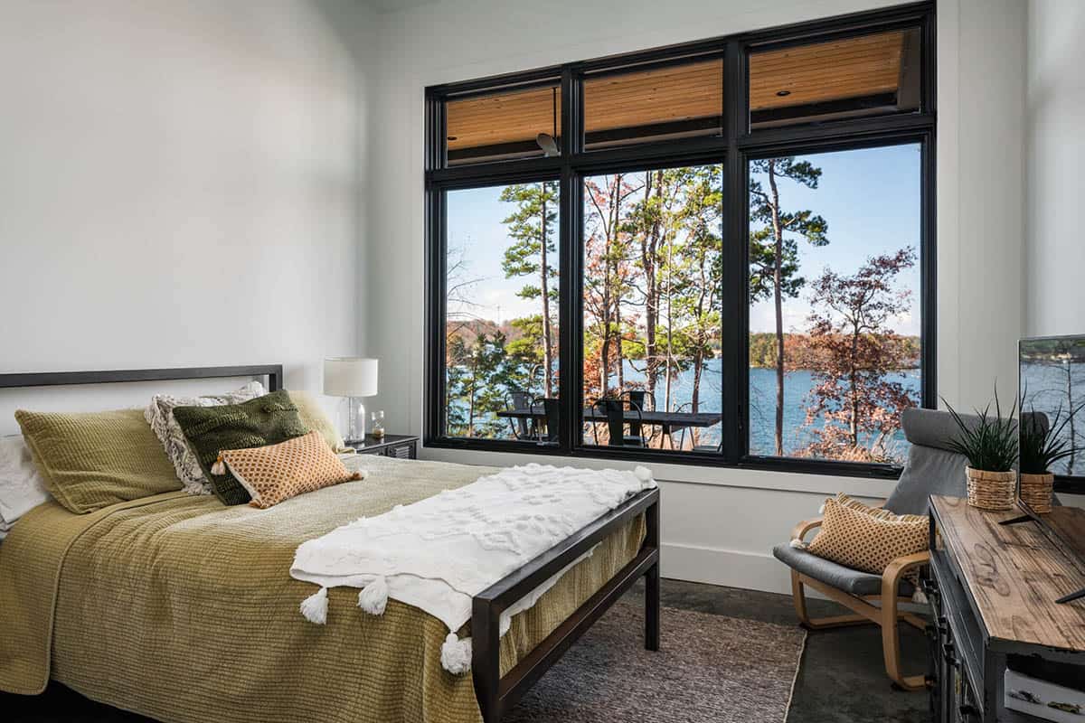 Guest bedroom with lake view through large black-framed windows