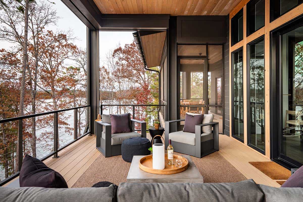 Screened porch with outdoor seating and lake views through trees