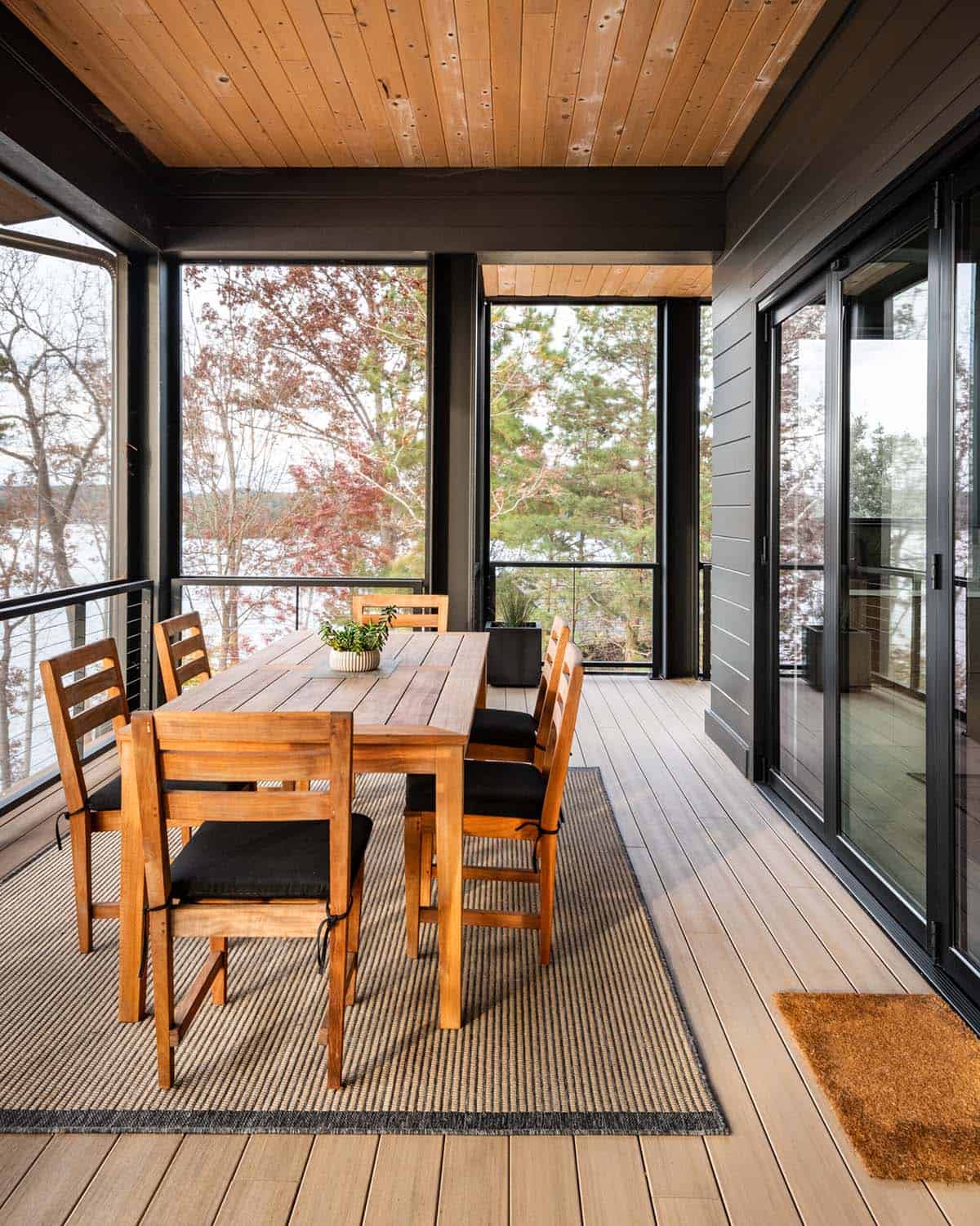 Screened porch dining area with wood table and black-framed glass