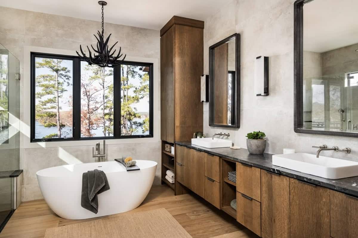Primary bathroom with freestanding tub, antler chandelier, and dual vanity