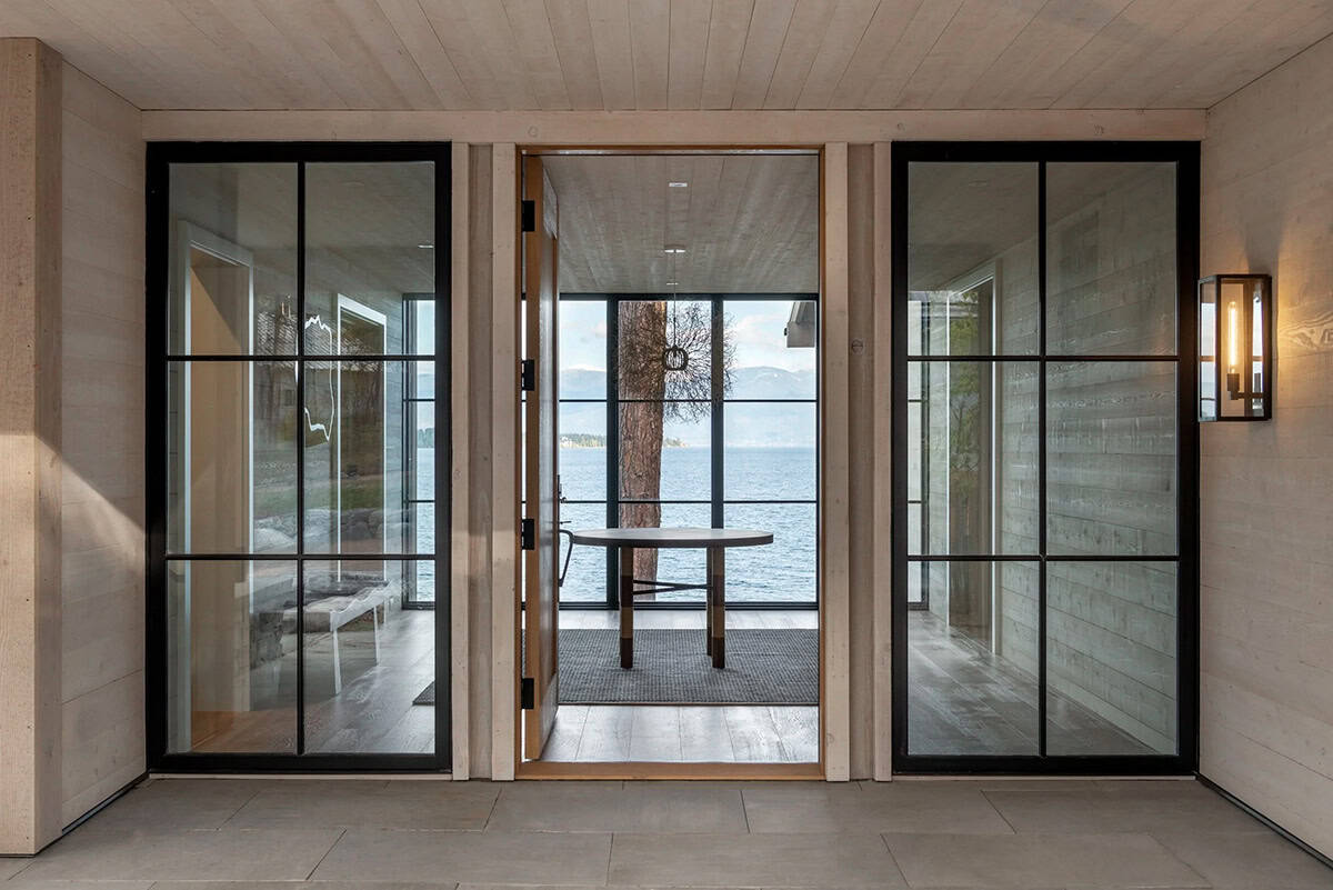 Glass entry doors framing a lake view dining table beyond