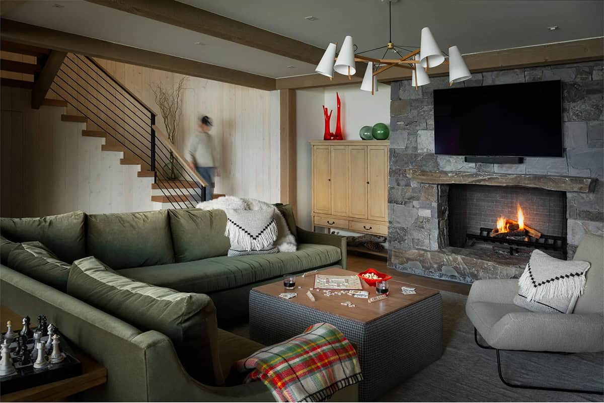 Lower-level lounge with stone fireplace and game table