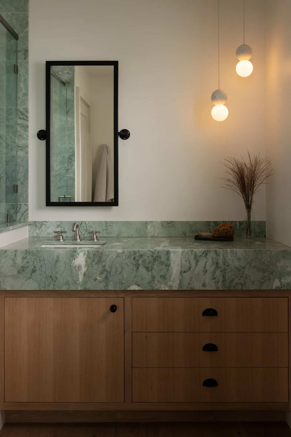 Powder room with green marble vanity and globe pendants