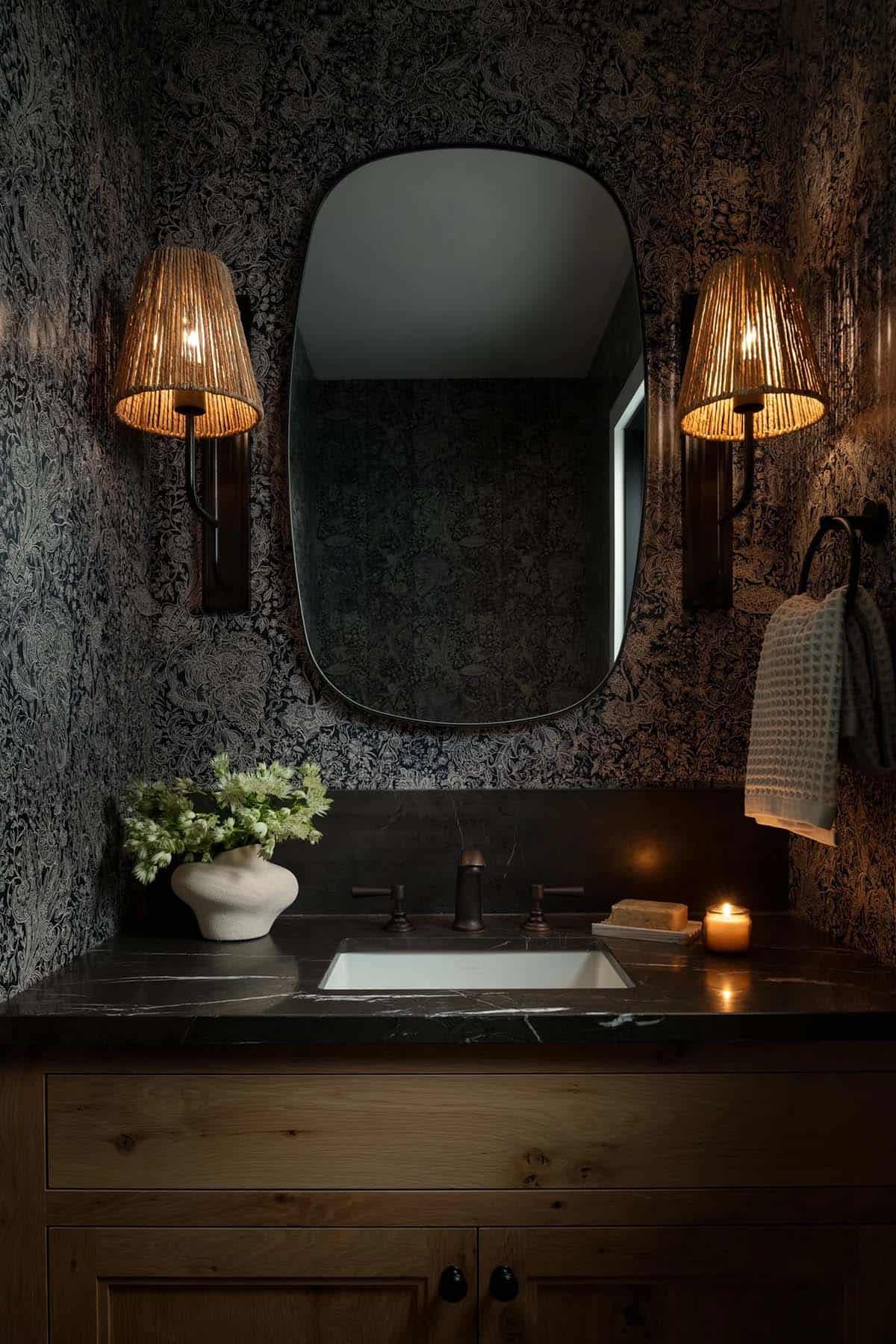 Dark powder room with patterned wallpaper and brass sconces