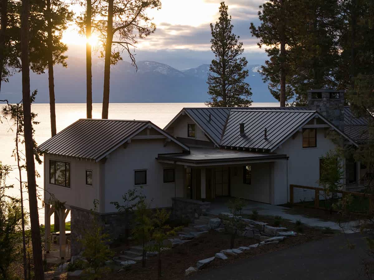 Lake house exterior at sunset framed by pine trees