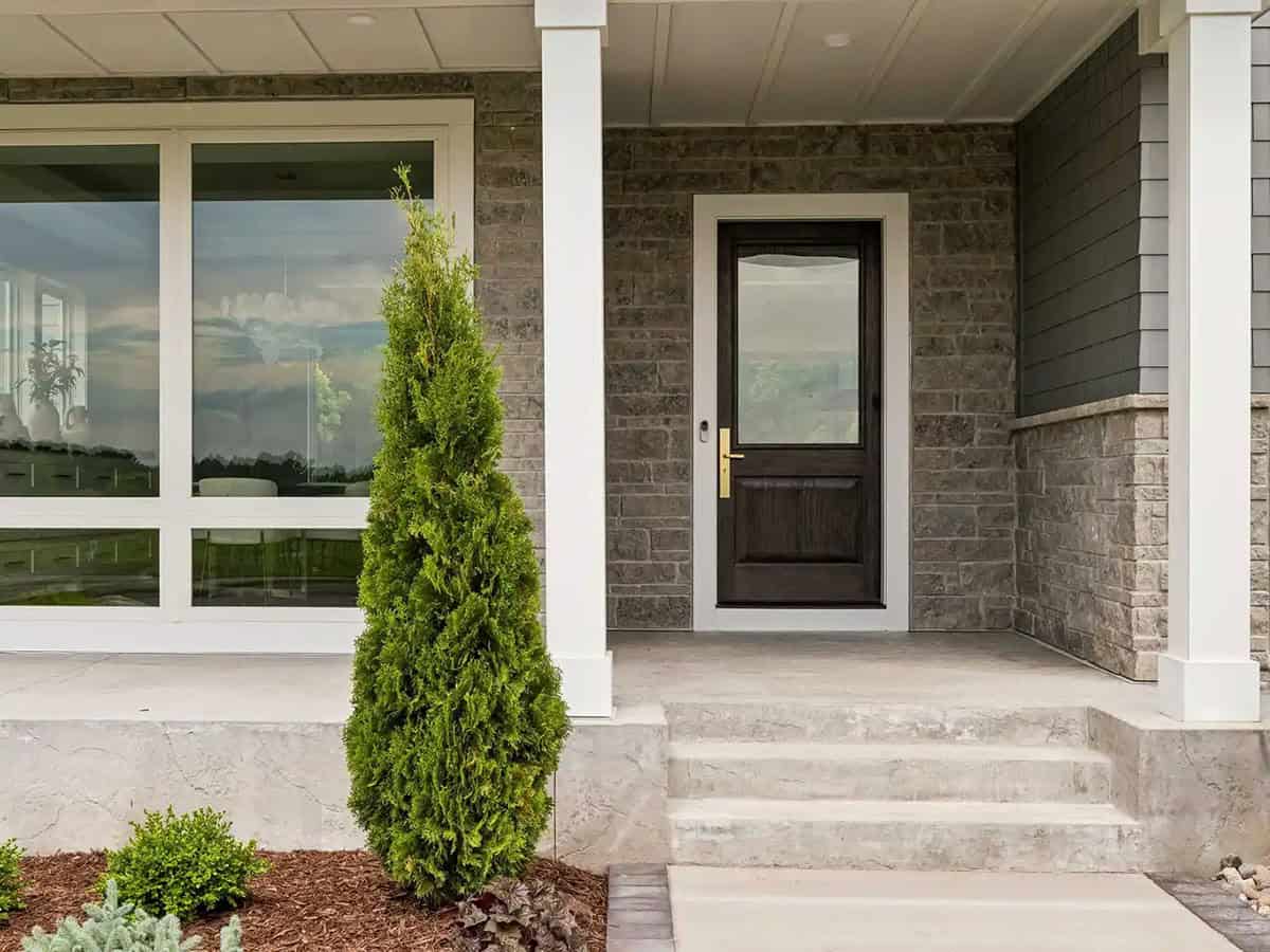 Covered entryway with stone accent wall and dark wood front door