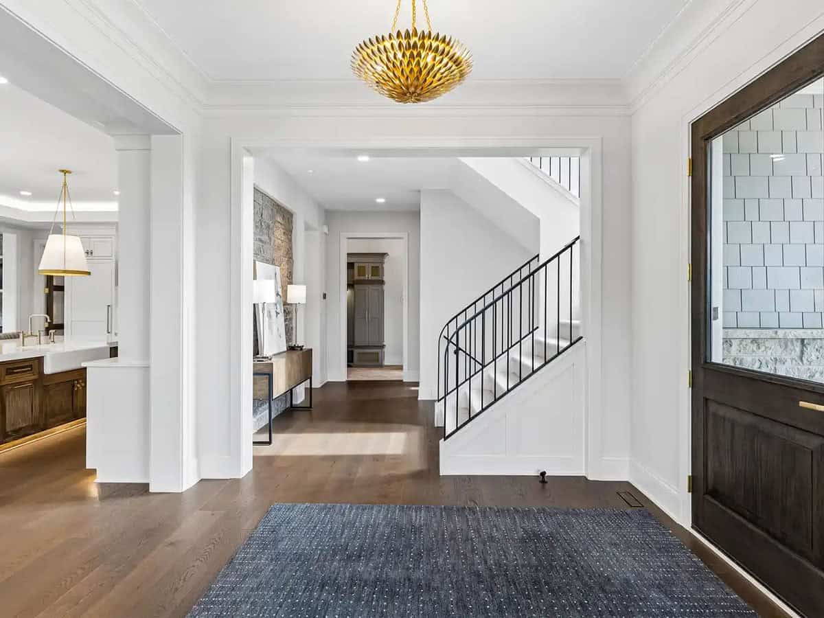 Foyer with curved staircase, dark wood door, and gold pendant light