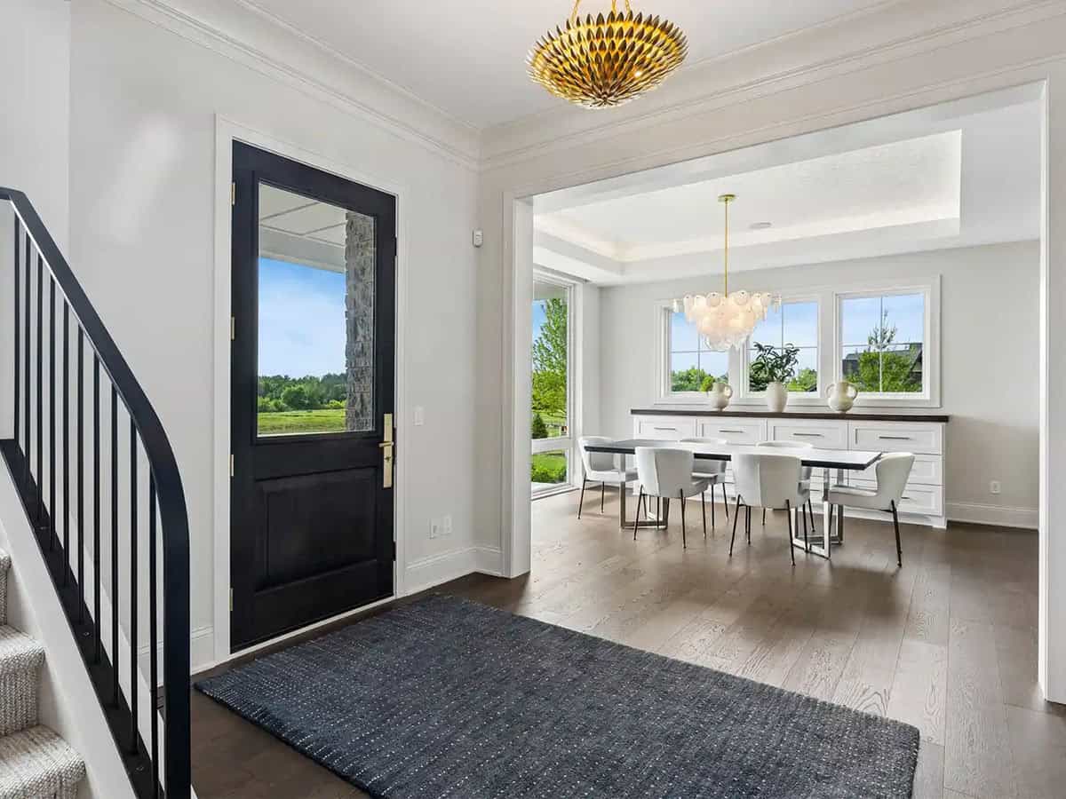 Entryway with black front door opening to dining room with chandelier