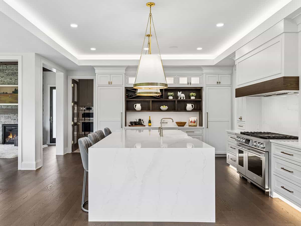 Kitchen with marble island, brass pendant lights, and stainless range
