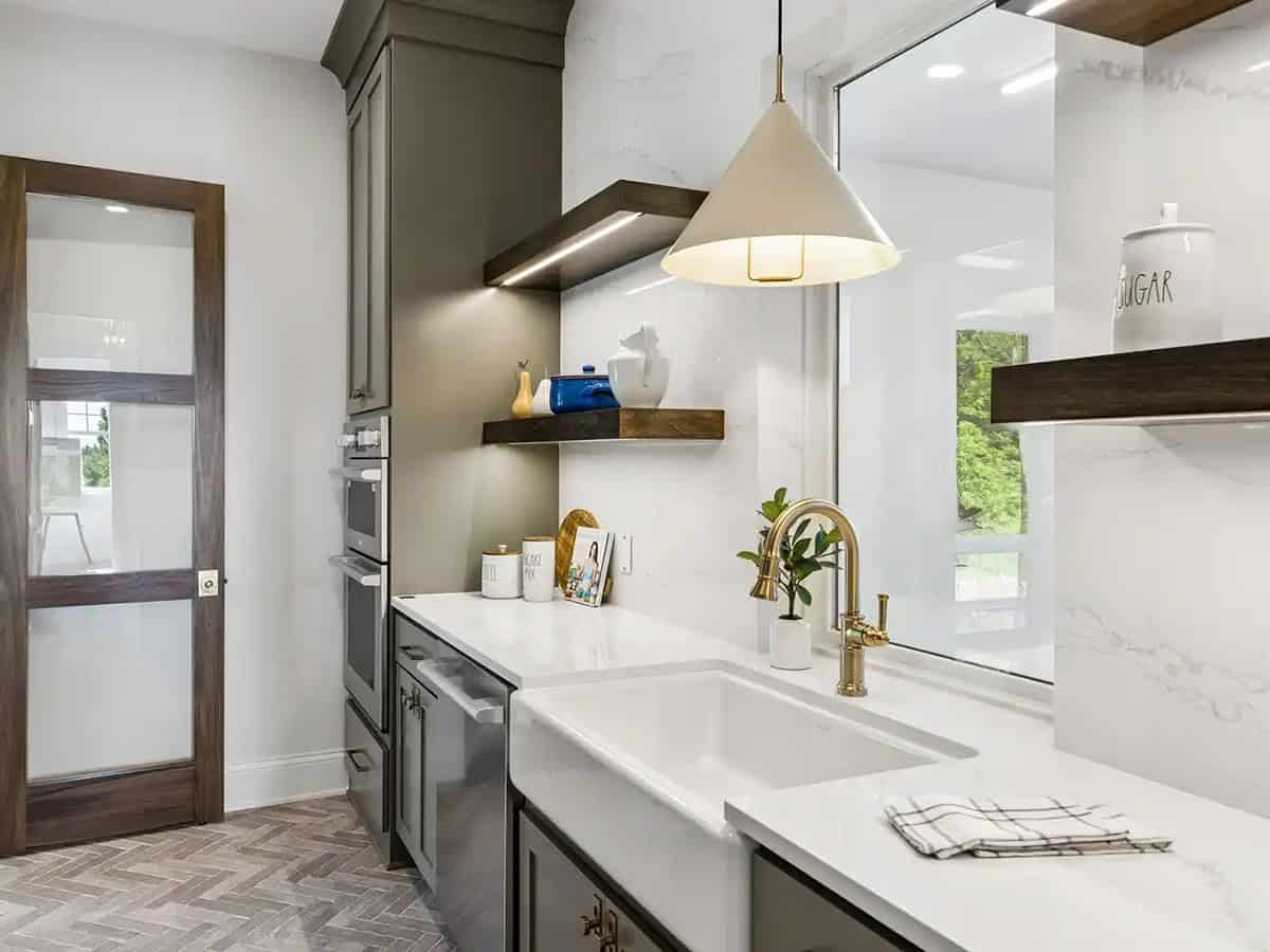 Butler's pantry sink with brass faucet and marble backsplash