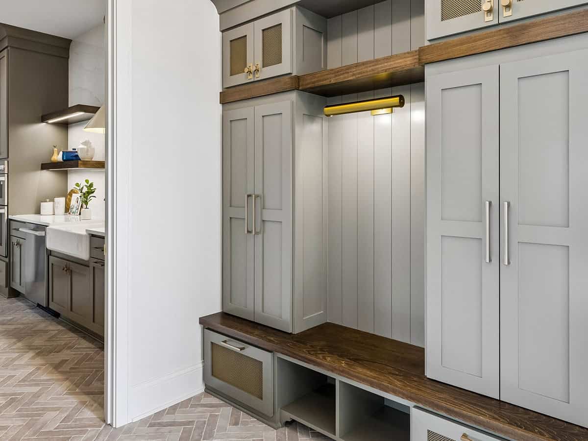 Mudroom lockers with herringbone tile floor and brass sconce
