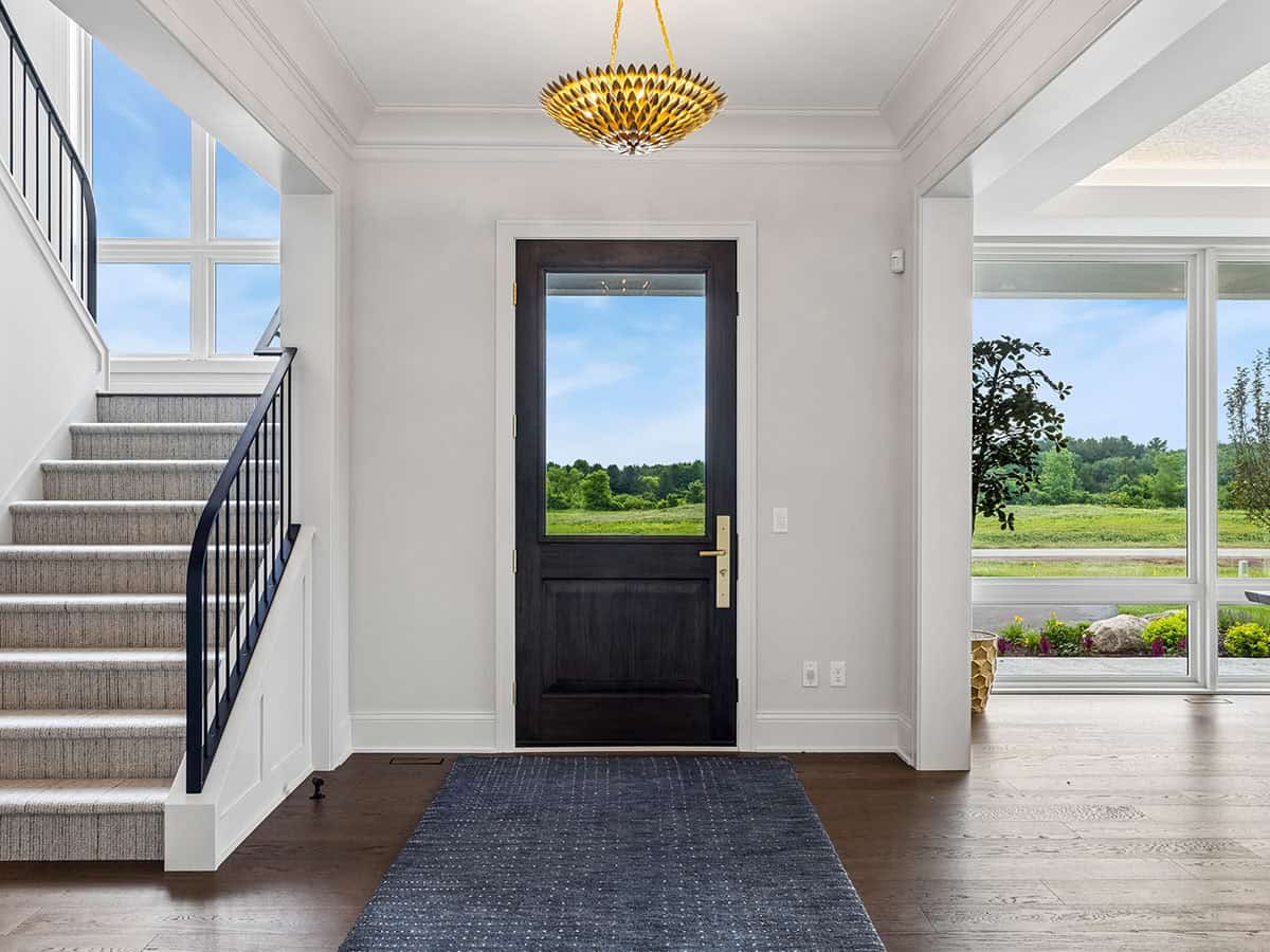 Entryway with dark front door and gold leaf-shaped pendant light