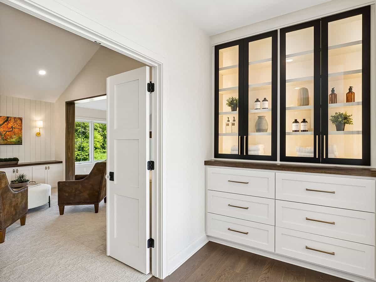 Hallway with built-in glass cabinet and leather armchairs beyond