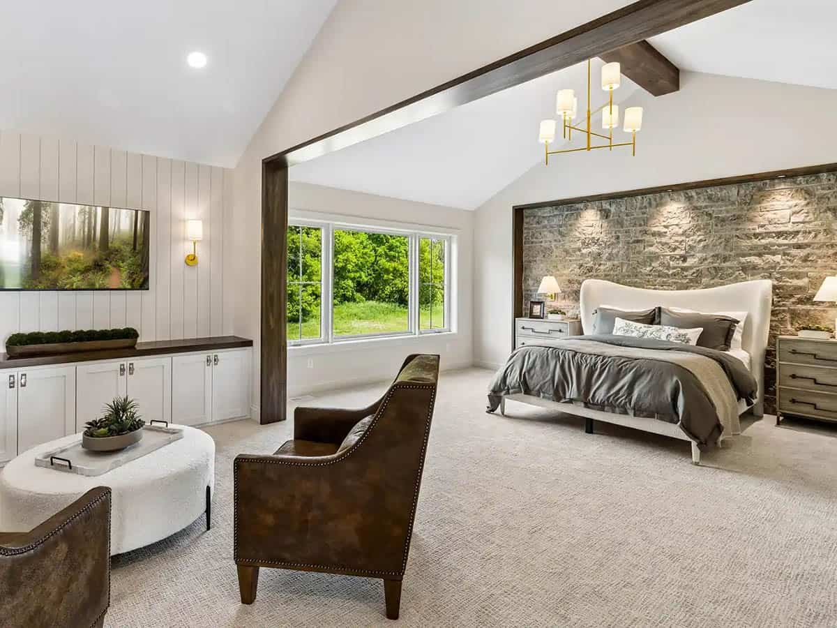 Primary bedroom with stone accent wall and vaulted wood-beam ceiling