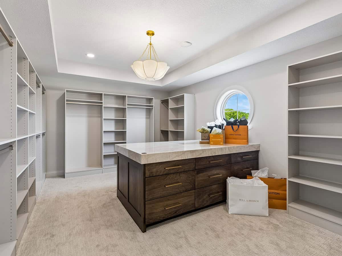 Empty walk-in closet with center island and built-in shelving