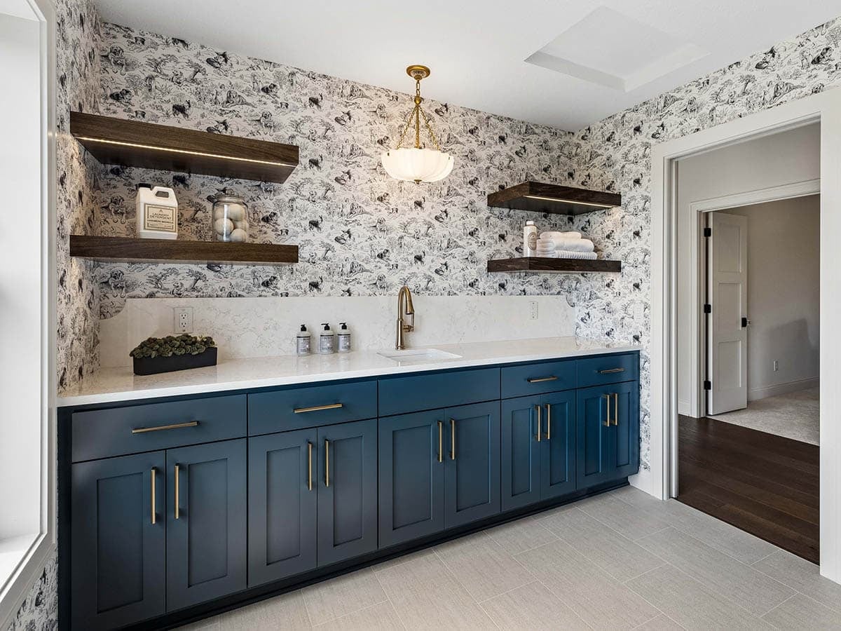 Laundry room counter with navy cabinets and floating wood shelves