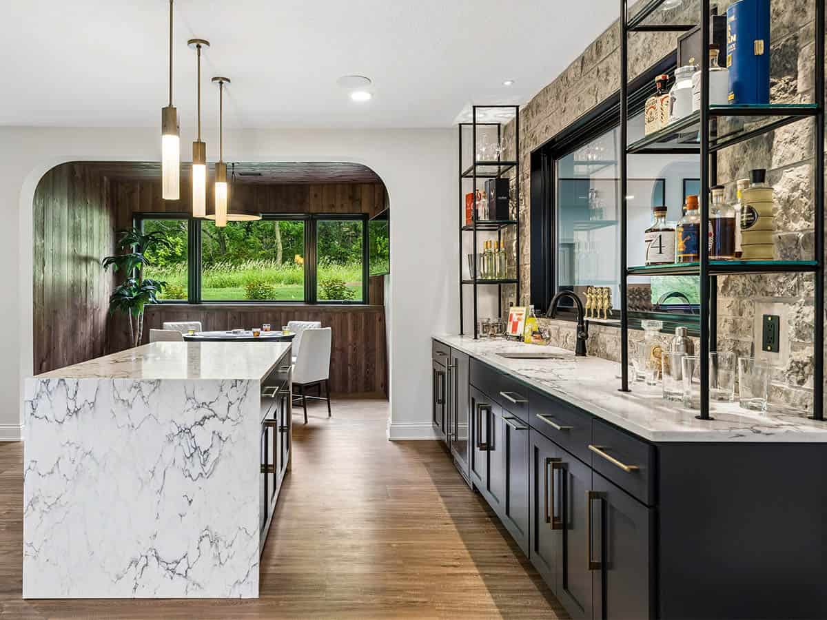 Wet bar with marble waterfall island and stone backsplash shelving