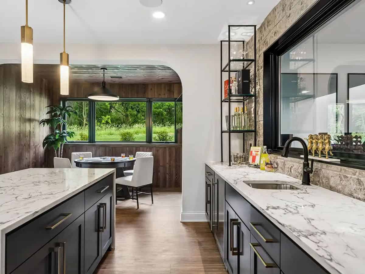 Wet bar counter with glass shelving overlooking wood-paneled game nook