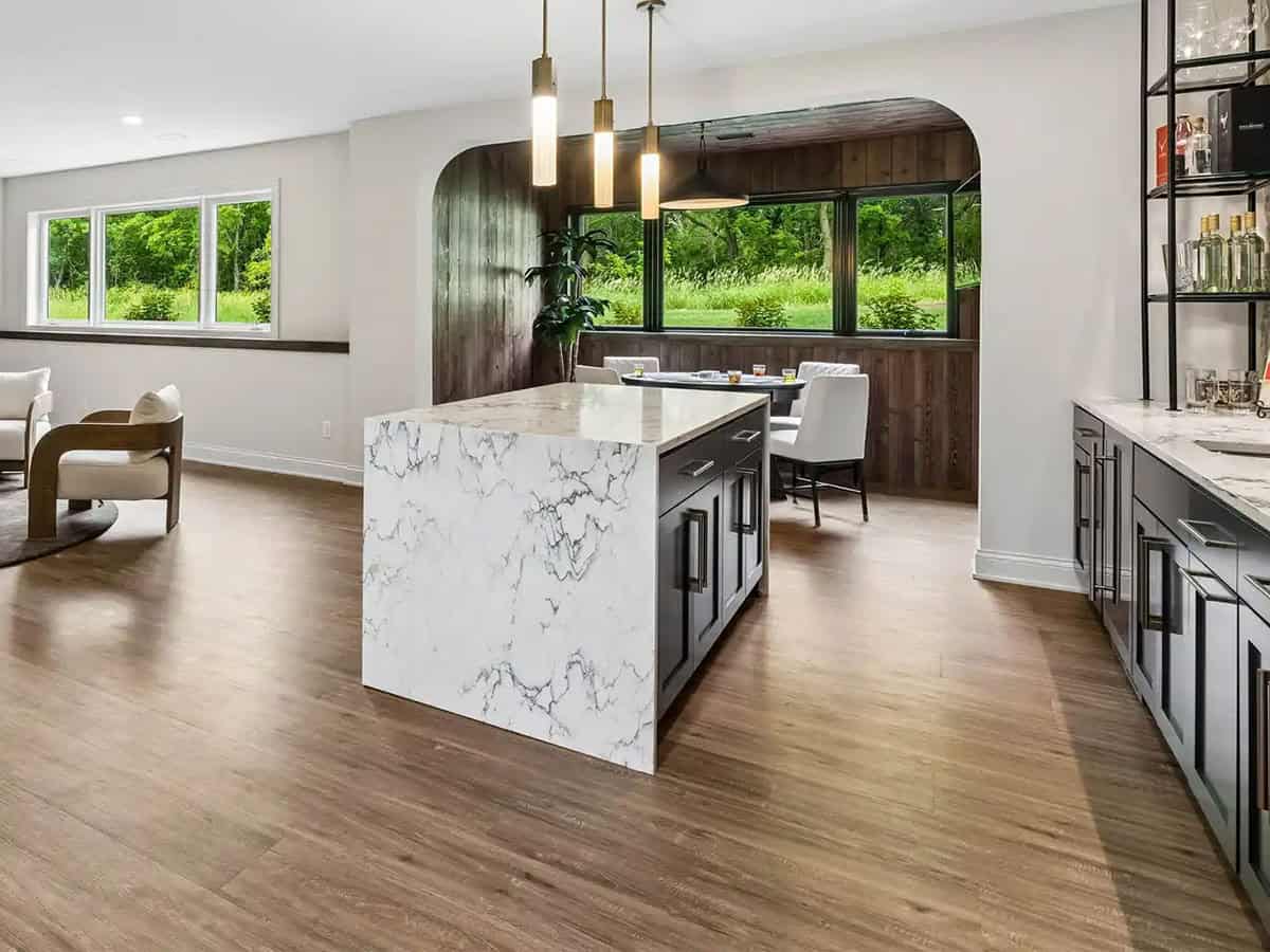 Lower-level marble island opening into wood-paneled poker nook