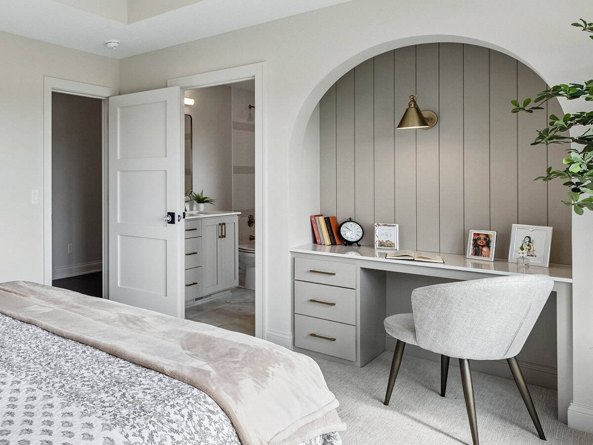 Bedroom with arched doorway into ensuite bathroom and built-in desk nook