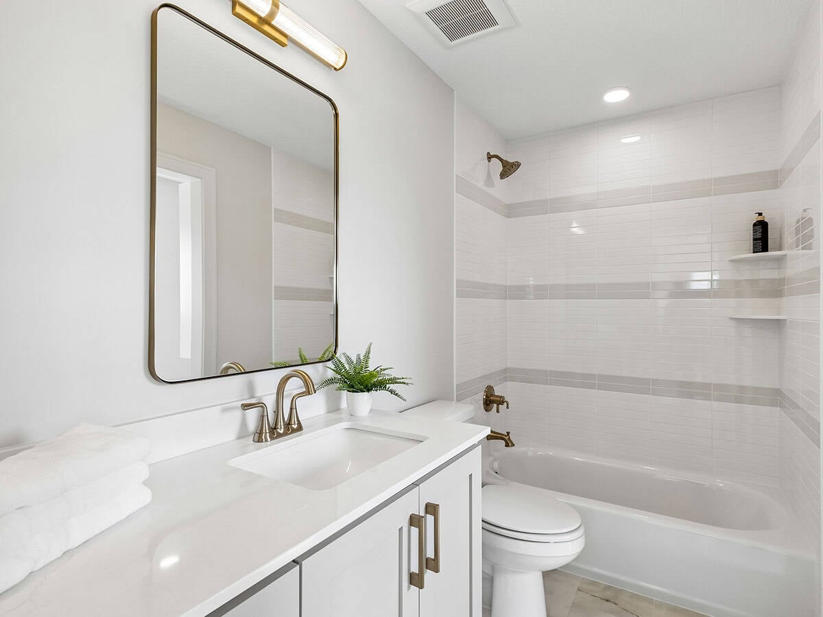 Bathroom with gold-framed mirror and tiled tub-shower combo