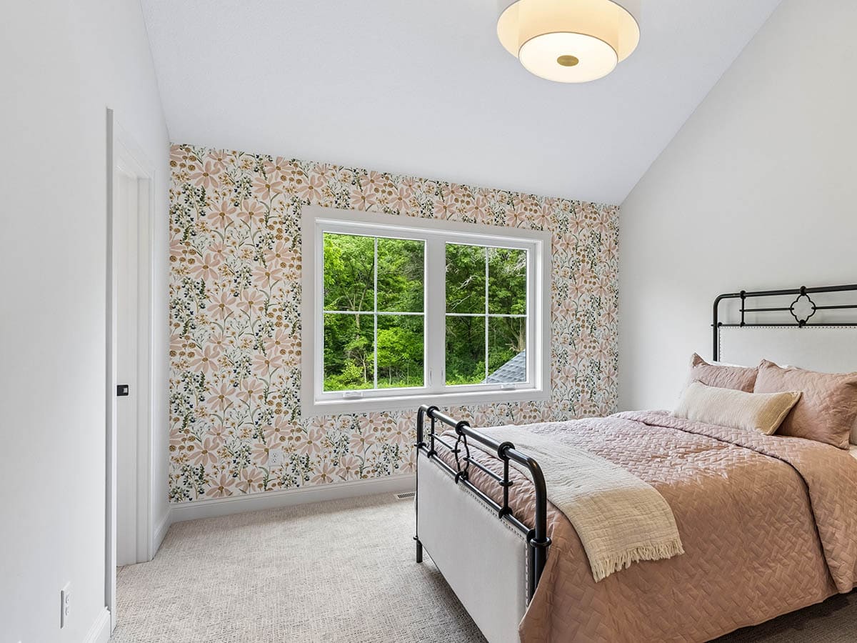 Bedroom with pink floral wallpaper and black metal bed frame