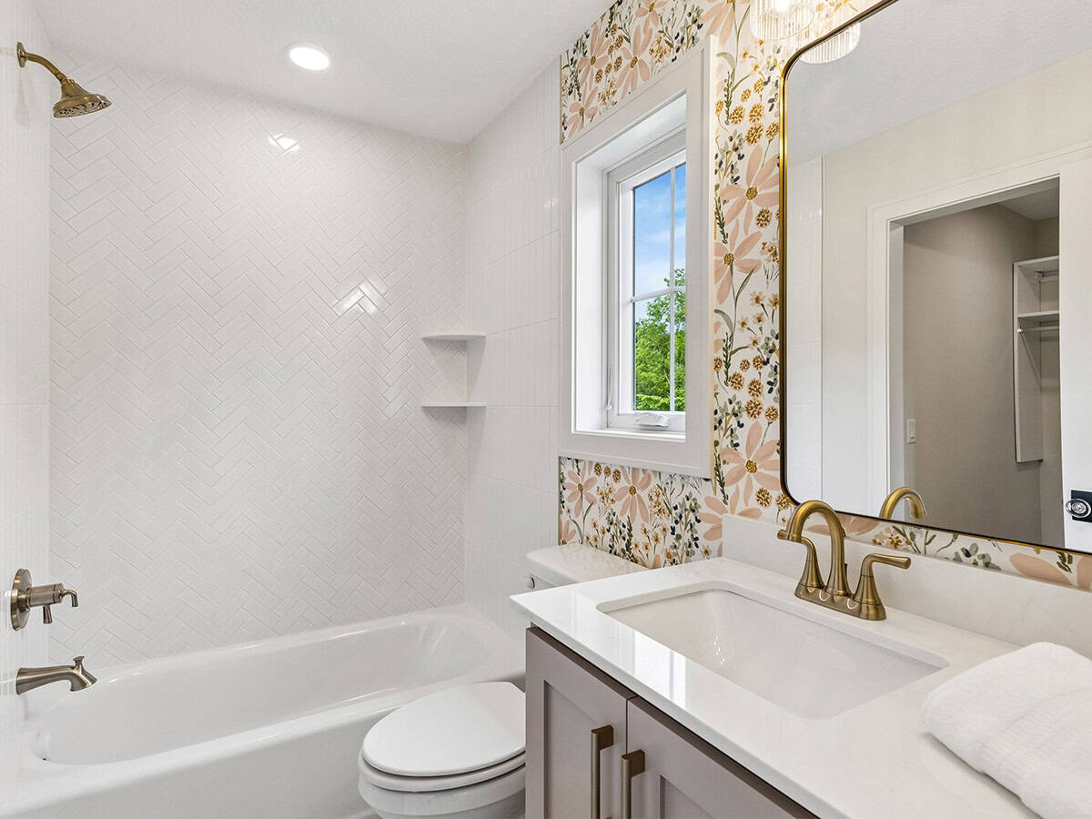 Bathroom with herringbone tile shower and floral wallpaper accent