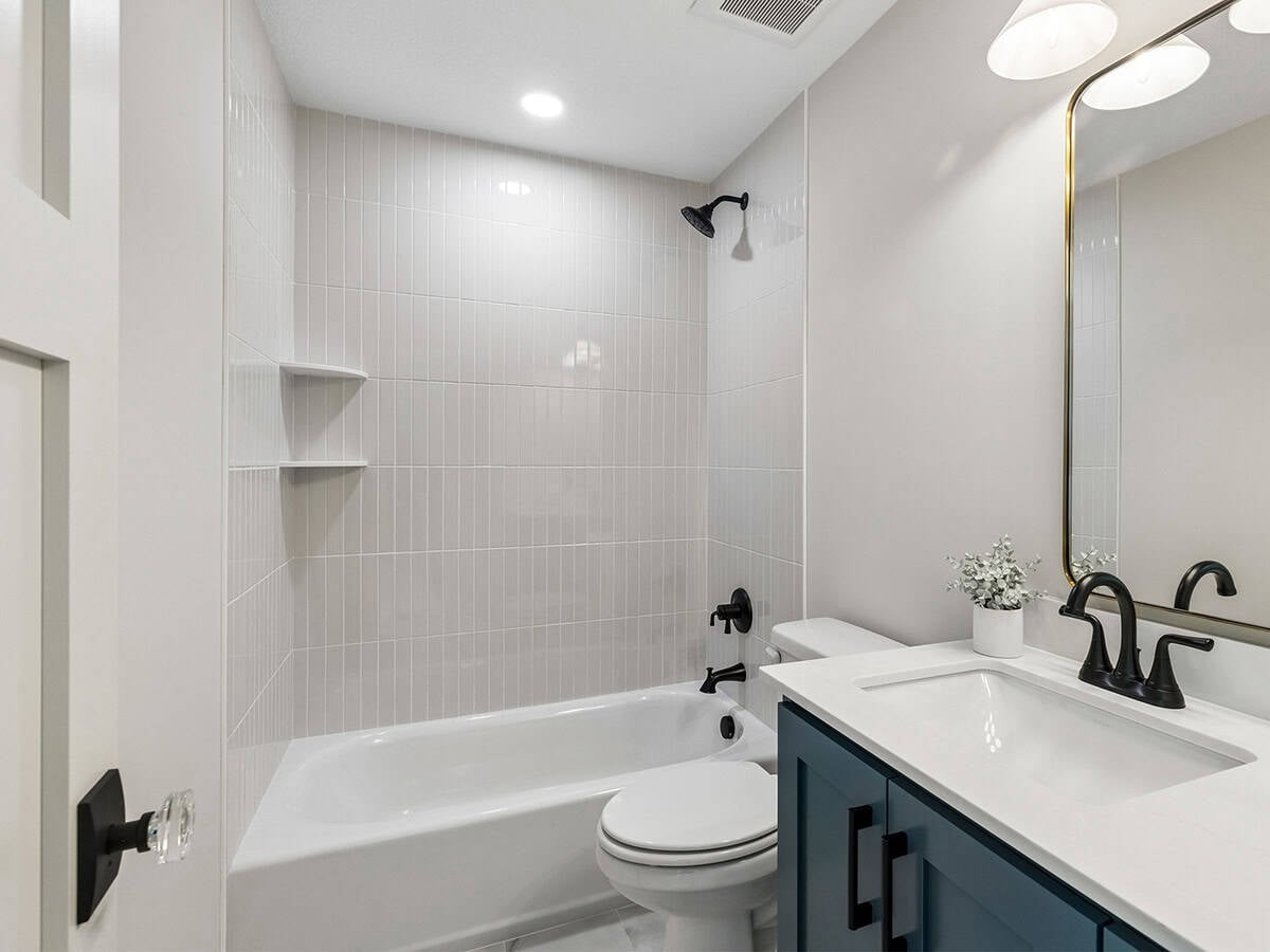 Bathroom with navy vanity and vertical tile tub-shower surround