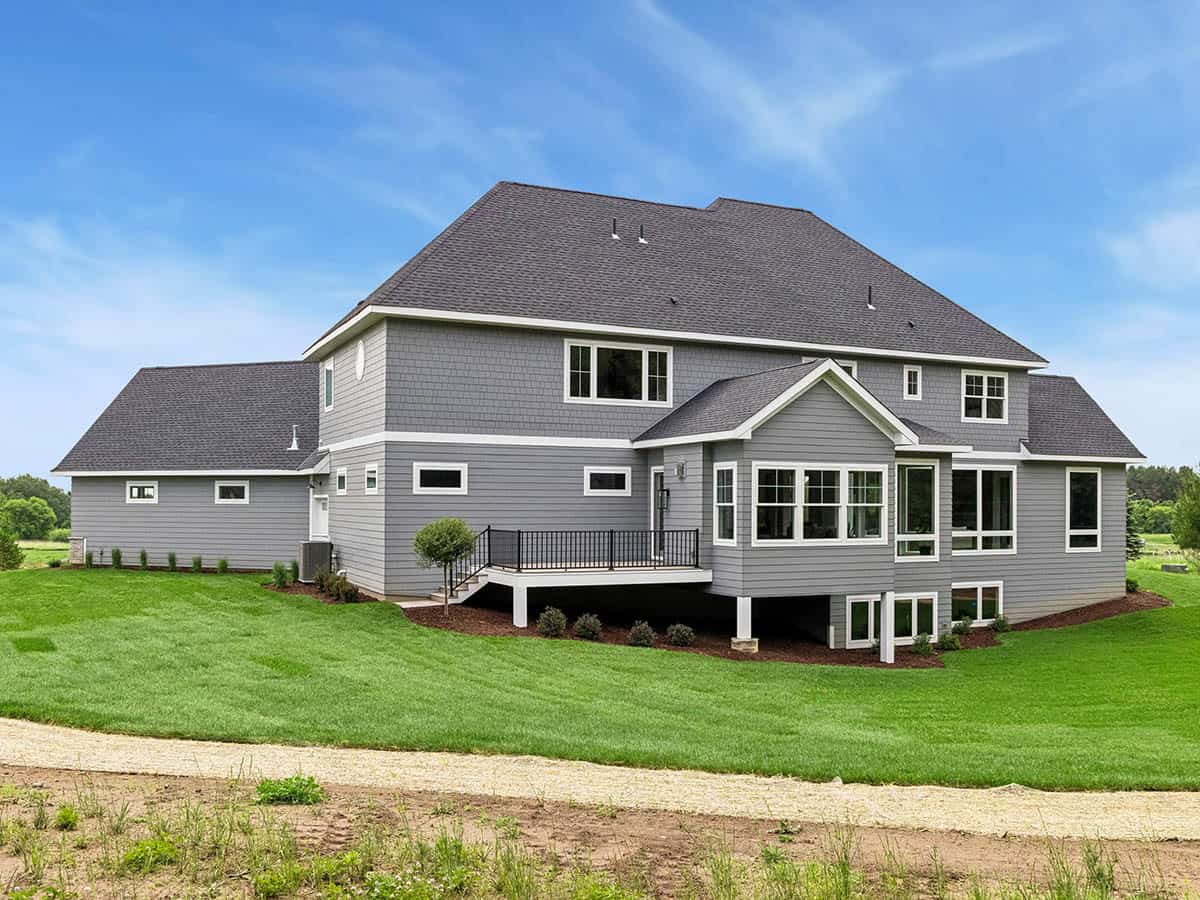 Side-rear exterior of gray house with deck and expansive lawn