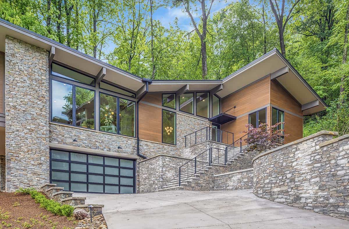 Daytime exterior view of the home's stone facade, glass garage door, and stairway entrance