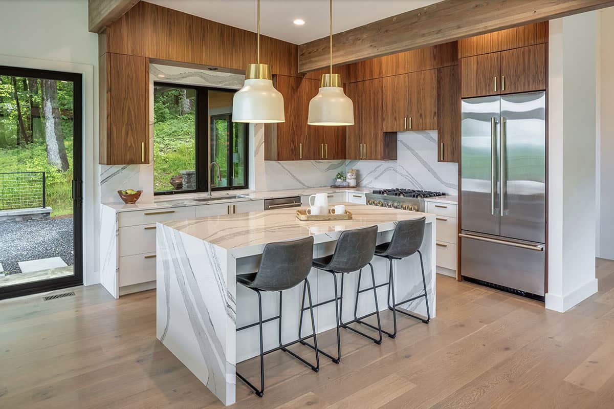 Kitchen view showing stainless steel refrigerator, walnut cabinets, and marble waterfall island